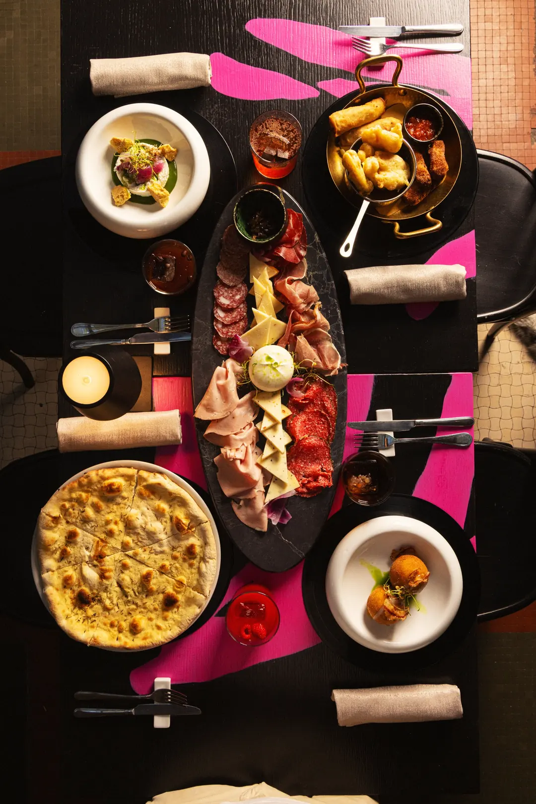 Tavola vista dall’alto con tagliere, fritto, pizza bianca e cocktail